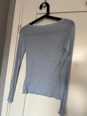Ljusblå långärmad topp - En enkel och stilren ljusblå långärmad topp med rund halsringning. Tunn och mjuk i materialet, perfekt att bära som den är eller under en jacka. Passar till både jeans och kjol för en avslappnad look.
