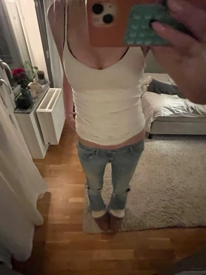 Lågmidjade jeans med hål - Säljer ett par ljusblå low waist jeans med bootcut passform. Jeansen har klassisk femficksdesign och är tillverkade i denim med lätt tvättad look. Perfekta för dig som gillar en avslappnad och trendig stil. har även hål och slitningar