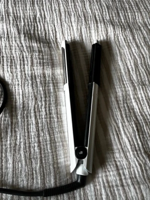 Svart och vit plattång - Snygg plattång i svart och vitt med slimmad design och greppvänligt handtag. Plattorna är släta och handtaget har silverfärgade detaljer med små nitar för bättre grepp. Perfekt för att styla håret snabbt och enkelt.