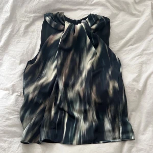 Mönstrad blus med knyt  - Snygg ärmlös blus med abstrakt mönster.