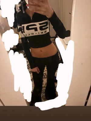 Svart croppad topp med halv dragkedja - Säljer en svart croppad topp som säger aspen ski club. Toppen har lång ärm, hög krage och halv dragkedja framtill. Brukar ofta ha den med svarta yoga pants eller svarta utsvänga leggings skit snygg på kroppen. Använder knappt 🫩