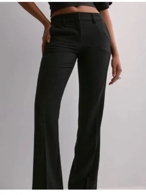 Svarta vida kostymbyxor - Säljer ett par svarta kostymbyxor med hög midja och vida ben. Byxorna har klassisk passform med pressveck och hällor för skärp. Perfekta för en clean och stilren look. Materialet känns mjukt och följsamt. Använt endast 1 gång! Använder inte kostymbyxor, köptes för 500 och säljer för 350 då byxorna är helt nya. Priset går att diskutera:)