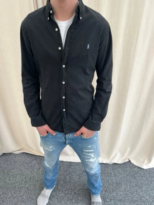 Svart skjorta från Ralph Lauren - Riktigt snygg svart skjorta från Ralph Lauren. Strl S, personen på bilden är 183 cm lång. Skicka gärna prisförslag. Kika in min profil för mer schyssta plagg.