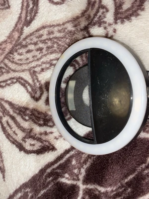 Selfie ring light med USB-laddning - Praktisk rund selfie ring light i svart och vitt, perfekt för att få bättre belysning vid sminkning eller fotografering. Den har en clip-on funktion och laddas via USB. Tillverkad i plast och enkel att använda på mobilen. Man kan ändra kallt till varmt ljus