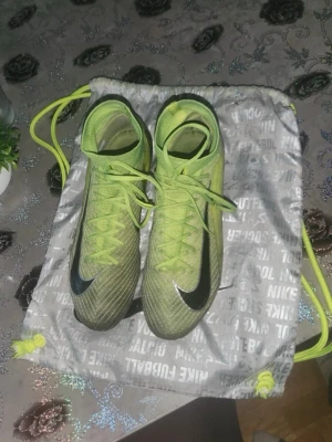 Nike Mercurial superfly 10 elite AG - Säljer ett par Nike Mercurial fotbollsskor i limegrönt med svarta detaljer och vita Nike-loggor. Skorna har snörning, hög krage för extra stöd och dobbar för spel på konstgräs. Tillverkade i syntetmaterial för bra grepp och lätt känsla på planen. Skorna är använda i cirka 2-3 månader och har inga slitage i materialet, det ända som har ändrats är greppet på materielet gripknit. Påse kommer med men inte original lådan