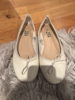 Vita ballerinaskor med rosett - Säljer ett par klassiska vita ballerinaskor från 157. Klippt upp därbak då de skavde i hälen