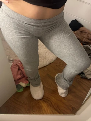 Grå mjuka bootcut leggings - Säljer ett par grå leggings i stretchigt och mjukt material. De har en enkel design med resår i midjan och sitter tight längs benen och löst nedertill.
