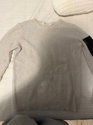 Beige stickad tröja från H&M - Stickad tröja från H&M i en ljusbeige färg med grovstickad struktur och rund halsringning. Tröjan har långa ärmar och ribbade muddar vid hals, ärmslut och nederkant. Perfekt för lager-på-lager och enkel att matcha.