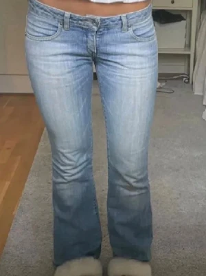 Ljusblå bootcut jeans från Replay - Säljer ett par ljusblå bootcut jeans från Replay med klassisk femficksdesign och snygga slitningar. Jeansen har låg midja och utsvängda ben, perfekta för en avslappnad och trendig look. Materialet är mjukt denim som sitter skönt hela dagen. Midjemåttet är 37 och innerbens längd 80🩷