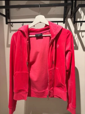 Juicy Couture Kofta Rosa - Jättejättefin tröja från Juicy Couture Knappt använd så det är därför jag säljer den Koftan är i helt nytt skick förutom söm som spruckit vid fickan (se bild)  Köpt på Raglady  I XS men skulle säga att den är XXS nästan (sista bilden är gul tröja men passformen och stl är samma) Färgen är fortfarande väldigt bright och ser ny och fräsch ut, samma med mjukheten i materialet