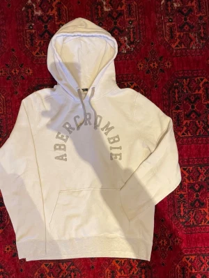 Abercrombie & Fitch Hoodie - Snygg ljusgrå hoodie från Abercrombie med stor huva och dragsko. Klassisk magficka och ribbade muddar. Stor logga i båge över bröstet. Inga defekter. Undrar du något är det bara att skriva😁🙌