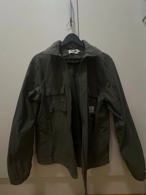 Militär grön jacka  - Snygg jacka med två bröstfickor och dragkedja framtill. Jackan har en klassisk krage och långa ärmar med resår vid ärmsluten. Perfekt för dig som vill ha en enkel och stilren jacka till vardags.
