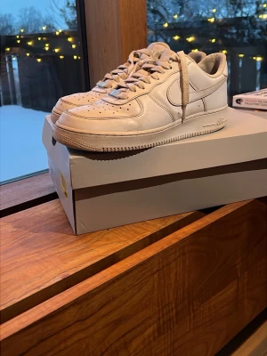 Nike Air Force 1 vita sneakers - Hej! Säljer nu mina Air Force 1, eftersom att de nu har blivit för små. De är ganska slitna. På sulorna på båda skorna har det blivit hål efter slitage men det är inget jag man märker när man har på dem. Kommer såklart med original lådan. Fördelarna med skorna är att man inte behöver vara särskilt försiktig med dem, de kan användas till vad som helst, billiga och att de matchar med allt. 