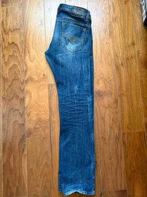 Diesel safado  - Säljer ett par klassiska blå jeans från diesel Jeans med raka ben och slitningar på knäna. Jeansen har fem fickor, normal midja och snygga detaljer på bakfickan. Perfekta för en avslappnad och trendig look.