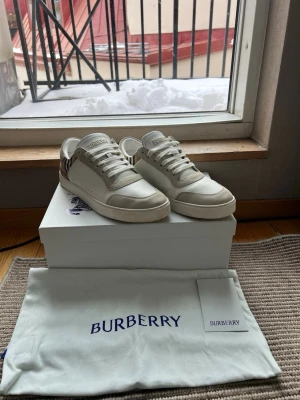 Vita Burberry sneakers med beige detaljer - Nypris 6900kr. Köpta från miinto. Allt Og medföljer. Garanterat äkta. Vid frågor eller funderingar är det bara att höra av sig🤙