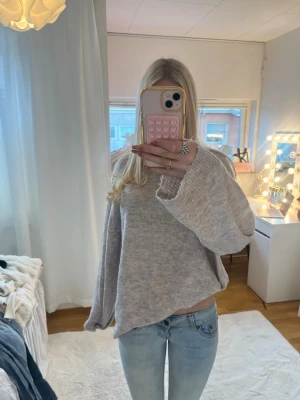 Beige oversized stickad tröja - Mysig beige stickad tröja med oversized passform och vida ärmar. Tröjan har en avslappnad look och är perfekt att bära till jeans. Materialet ser ut att vara mjukt och skönt, perfekt för kyligare dagar.
