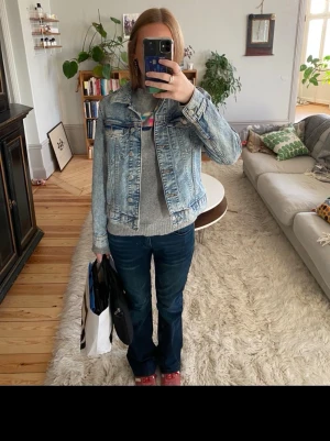 Ljusblå klassisk jeansjacka - Snygg ljusblå jeansjacka med klassisk passform och krage. Jackan har två bröstfickor med lock och knappar framtill. Perfekt att slänga över en hoodie eller tröja för en avslappnad look.