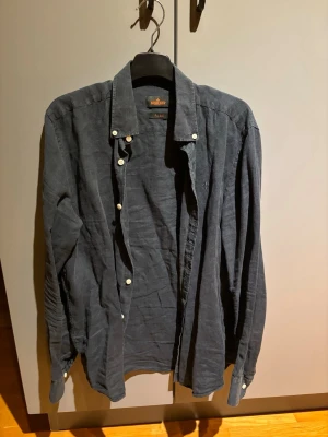 Mörkblå linneskjorta från Morris - Stilren mörkblå skjorta från Morris i linne med klassisk krage och vita knappar. Säljer den då den blivit för liten för mig(193/74kg). Skjortan har lång ärm och en avslappnad passform, perfekt för en trendig och bekväm look. Bara att höra av dig vid minsta fundering🤗