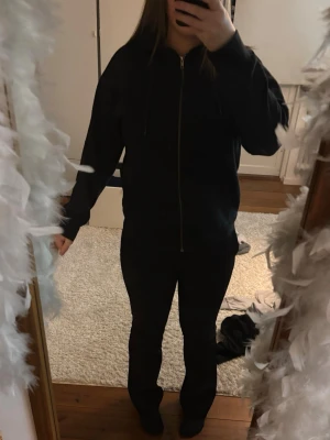 Svart zip hoodie med Luva - Säljer en svart hoodie med dragkedja och huva. Hoodien har en enkel och clean design med långa ärmar och dragsko i huvan. Perfekt för dig som gillar en avslappnad och stilren look. Materialet känns mjukt och bekvämt. Jag säljer pga av att jag inte har nån rum i gaberoben.