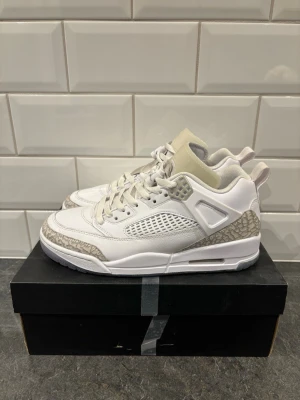 Vita Air Jordan 3 sneakers - Snygga vita Air Jordan 3 sneakers med klassiska elefantmönstrade detaljer i grått runt tå och häl. Skorna har meshpaneler på sidorna, vita skosnören och en vadderad plös med Jumpman-logga. Tillverkade i läder och textil för en clean och sportig look.