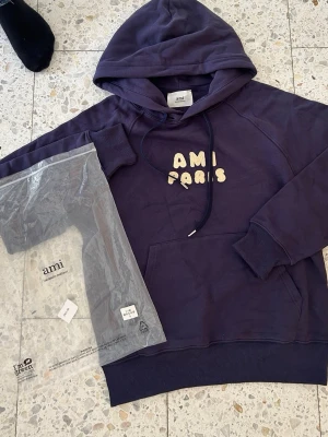 Ami Paris hoodie -Mörkblå - Säljer en snygg lila hoodie från Ami Paris med broderad text på bröstet. Storlek S pris kan diskuteras vid snabb affär. 