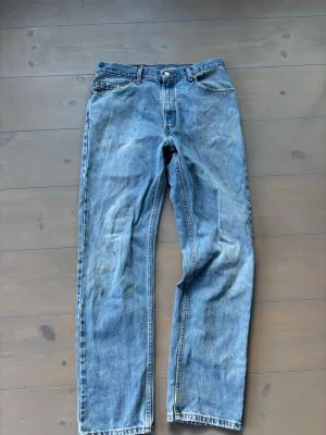 VINTAGE Levi’s 501 - Klassiska blå jeans från Levi's med rak passform och fem fickor. Jeansen har normal midja, knappgylf och är tillverkade i slitstark denim. Perfekta för en avslappnad och tidlös look.