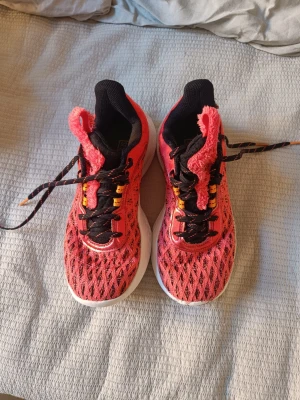 Curry orangea basketskor - Orange/rosa Curry skor från Under Armour med svart mesh och orange detaljer. Skorna har vit, mönstrad sula och snörning med svarta och orangea skosnören. Ovandelen är ventilerande mesh och loggor finns på sidan och sulan. Perfekt för dig som gillar sportig stil.