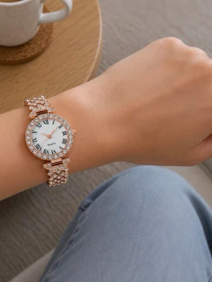 Glittrig guldfärgad klocka med stenar - Snygg guldfärgad klocka med glittrande stenar runt hela boetten och armbandet. Klockan har vit urtavla med romerska siffror och tunna guldfärgade visare. Perfekt accessoar för dig som gillar bling och vill sticka ut.