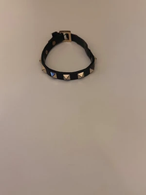 Valentino armband - Svart valentino armband med guldiga spikar. Armbandet är i helt okej skick men behövt limma ihop det lite på ett ställe. Men det funkar toppen!