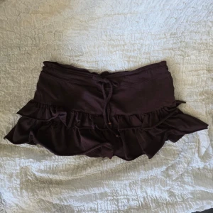 Brun minikjol med volang och snörning - Supersnygg minikjol med volanglager och snörning i midjan. Kjolen har även shorts under och är bekväm att ha på sig. Passar storlek XS. Det går bra att köpa via "köp nu" knappen 💞