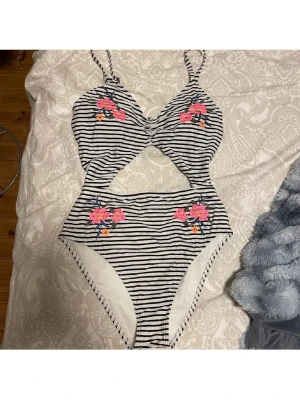 Randig baddräkt från hollister - Säljer en svartvit randig baddräkt med utskärning i midjan och broderade blommor🌷storlek M men mer som en xs-s