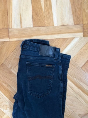 jeans från Nudie - Snygga jeans från Nudie Jeans med klassisk femficksdesign och läderpatch bak i midjan. Jeansen har en smal passform och är tillverkade i stretchigt denim som ger en bekväm känsla. Perfekt för dig som gillar en stilren look.