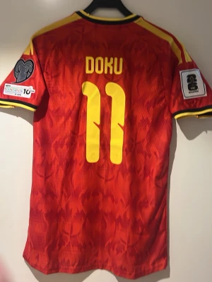 Belgien Vm 2026 Doku #11 - En Belgien 🇧🇪 VM 2026 tröja med Doku #11 Spelar version Storlek L