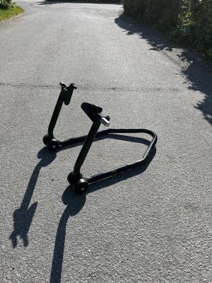 Svart motorcykellyft i metall - Säljer en svart motorcykellyft i robust metall med två hjulpar och justerbara armar. Perfekt för att lyfta bakdelen på motorcykeln vid service eller förvaring. Enkel att använda och smidig att förvara tack vare sin kompakta form.