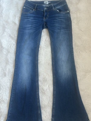 Blå bootcut jeans med slitningar - Snygga blå bootcut jeans med lätt slitna detaljer och klassisk femficksdesign. Jeansen har en utsvängd passform från knät och är tillverkade i denim. Perfekta för dig som gillar retrovibbar och vill ha ett par jeans som sticker ut. Skriv privat om ni vill ha fler bilder eller något annat❤️👍🏼🤗
