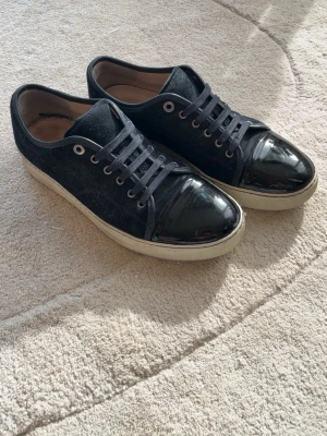 Lanvin Mörkblåa - Mörkblåa Lanvins med vit sula och glansig lack vid tårna. Skorna är använda ett par gånger men är fortfarande i bra skick. Är i 42 men passar även 43. 