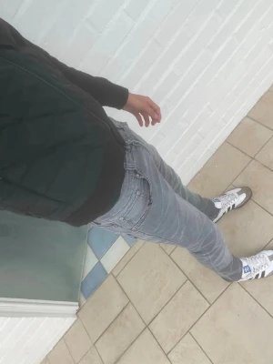 Dondup George Slim Fit Jeans – Grå tvätt – W31 - Säljer ett par Dondup George jeans i snygg grå tvätt. Slim fit-modell med stretch som ger en bekväm passform och sitter bra på kroppen. Klassisk premiumdenim från Dondup med D-logga på bakfickan och stilrena detaljer.  Storlek: W31 Passform: Slim fit Färg: Grå tvätt Skick: Mycket bra skick  Mått: • Midja: ca 41 cm liggande (82 cm omkrets)  Perfekta till både vardag och mer uppklädda outfits. Skriv gärna vid frågor eller om du vill ha fler bilder eller mått.