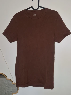 Tshirt unisex - Säljer en basic brun t-shirt från Levi's med klassisk rund hals och korta ärmar. Tillverkad i mjuk bomull och har den ikoniska röda Levi's-taggen i sidan. Perfekt till jeans eller shorts för en enkel och clean look. Passar både kille som tjej 