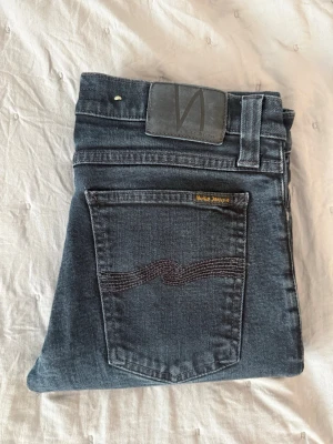 Nudie jeans svarta W30 L34 - Hej! Säljer nu ett par riktigt fina jeans från Nudie Jeans. Modell:Tight Long John  Storlek: W30/L34  Sitter snyggt och är enkla att matcha till allt, oavsett om du kör casual eller lite mer uppklätt.  Hör gärna av dig vid intresse 🙂  Mvh Elias