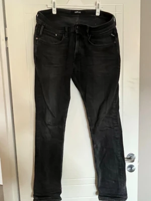 Svarta  jeans från Replay - Snygga svarta  jeans från Replay med klassisk femficksdesign och diskret logotyp på fickan. Jeansen har en lätt tvättad look och är tillverkade i stretchigt denim som ger en bekväm passform. Perfekta för dig som gillar en modern och stilren look. Strl 30/32
