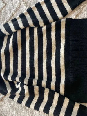 Svart och beige randig stickad tröja - Helt oanvänd och ny randig stickad tröja i svart och beige med ränder. Tröjan är i helt nytt skick, tyvärr utan prislapp.  Tröjan har långa ärmar och ribbstickade muddar vid ärmslut och nederkant.  