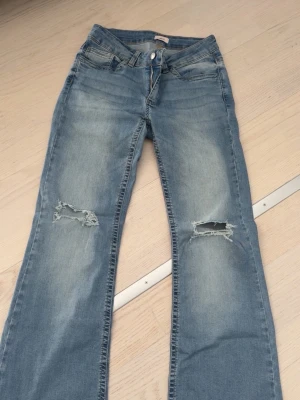 Ljusblå Nelly Jeans   - Säljer ett par ljusblå jeans med slitningar och hål på knäna. Är 169 och de sitter perfekt på, hör av dig vid eventuella frågor! 🩷