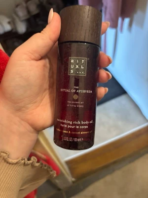 Rituals The Ritual of Ayurveda kroppsolja - Nourishing rich body oil från Rituals The Ritual of Ayurveda med doft av indisk ros och söt mandelolja. Flaskan är mörkröd med svart lock och rymmer 100 ml. Perfekt för att återfukta och ge huden en lyxig känsla.