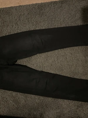 Svarta skinny jeans från Replay - Säljer ett par svarta skinny jeans från Replay. Jeansen har en tight passform och klassisk femficksdesign. Materialet är stretchigt för extra komfort och de har Replay-loggan broderad vid fickan. Perfekta för en trendig och stilren look.