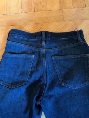 Mörkblå jeans från Zara - Snygga mörkblå jeans från Zara med raka ben och klassiska bakfickor. Jeansen har hög midja och är tillverkade i ett mjukt denimtyg som sitter skönt. Perfekta till en avslappnad look och funkar året runt.