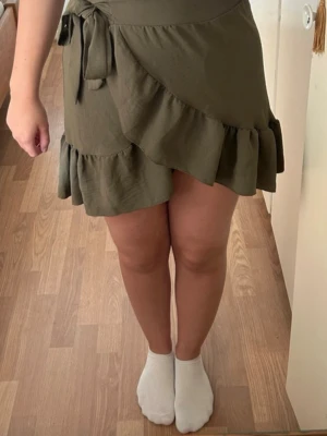 Omlottkjol - Militärgrön omlottkjol med knytband. I mycket fint skick. Material: Polyester