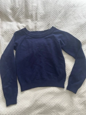 Mörkblå stickad tröja - Mysig mörkblå stickad tröja från FB Sister Knitwear. Tröjan har rund halsringning, modellen är lite kortare i magen, ribbade muddar vid ärmslut och nederkant samt en enkel, klassisk design som passar till det mesta. Perfekt för lager på lager under kyliga dagar. Tröjan är i väldigt bra skick!