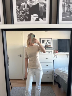 Beige kortärmad topp med båtringning - Säljer en stilren beige topp med korta ärmar och båtringning. Toppen har en slim passform och är gjord i ett mjukt bomullsmaterial som känns skönt mot huden. Perfekt för dig som gillar en enkel och clean look.