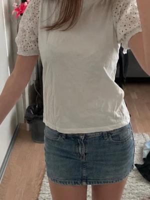 Blå jeanskjol mini - Säljer en blå kort jeanskjol med klassisk femficksmodell och dragkedja framtill. Kjolen har en rak passform och är tillverkad i denim, vilket ger en cool och tidlös look. Perfekt för dig som gillar enkel och stilren denim.