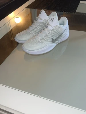 Vita Nike sneakers med silverdetaljer - Nike Sabrina 2 Metallic Silver   Säljer ett par Sabrina Ionescu signaturskor, modellen Sabrina 2 Metallic Silver. En av de senaste modellerna, designad för basket – men passar lika bra för alla spelare oavsett kön.  Skorna är köpta nya för cirka 3 månader sedan och är endast använda 2–3 gånger, vilket syns tydligt på skicket – de är i princip som nya.  Väldigt bekväma, lätta och ger bra känsla på planen, vilket gör dem perfekta för dig som vill ta ditt spel till nästa nivå.